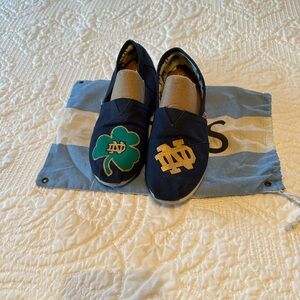 Navy Toms decorated with Notre Dame logos.